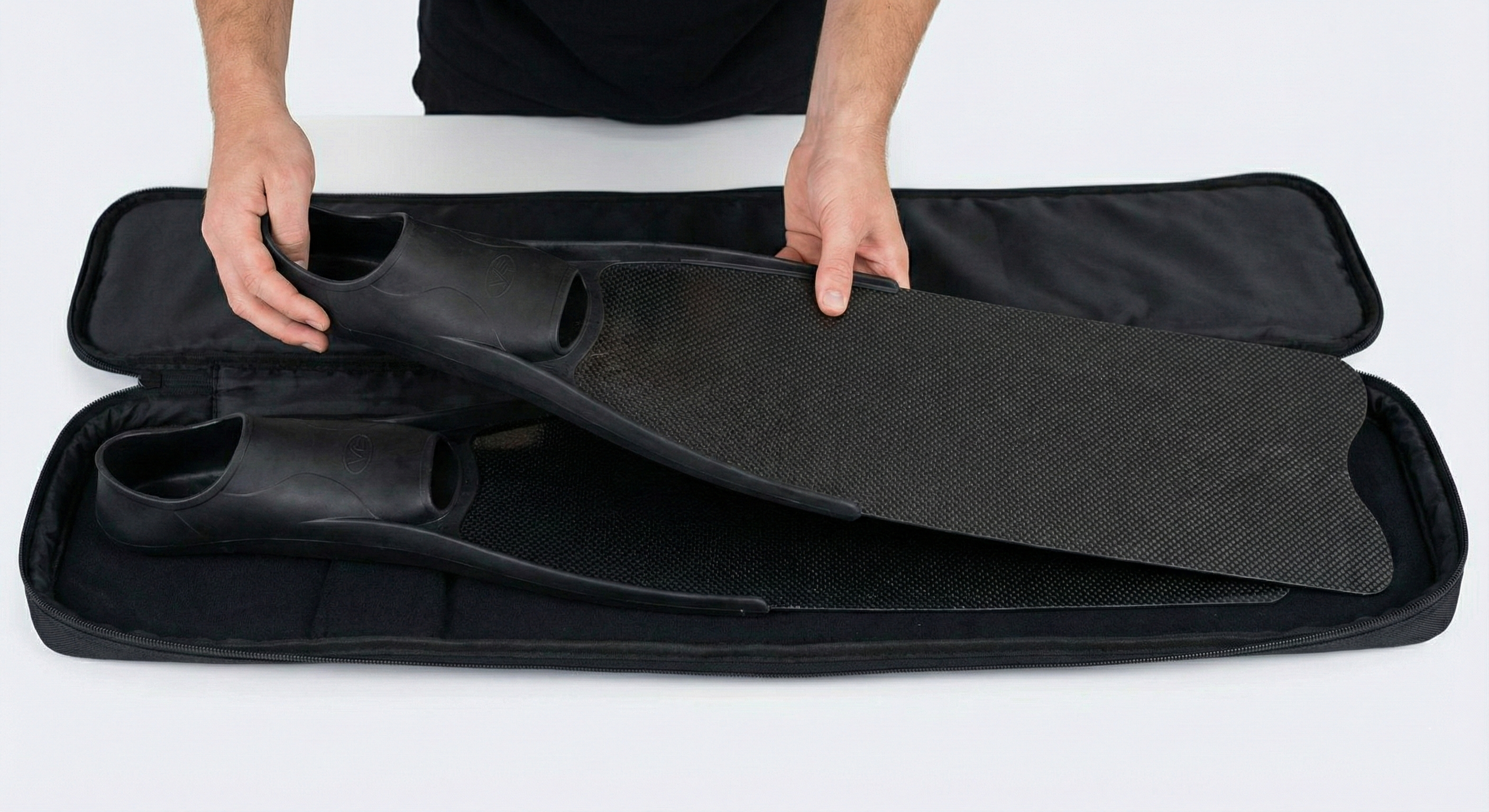 The fins are being placed into a padded bag, lying flat to prevent warping and protect them from scratches.